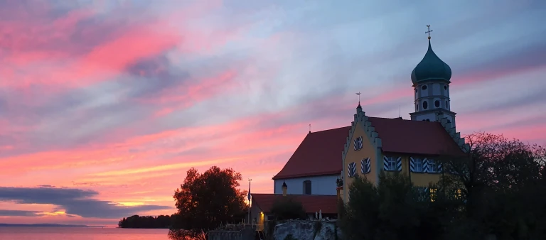 Wasserburger Halbinsel am Bodensee mit Kirche, Hafen und rötlichem Abendhimmel